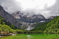 Cloud-enshrouded peak of Mt Chenrezi with a glacial lake